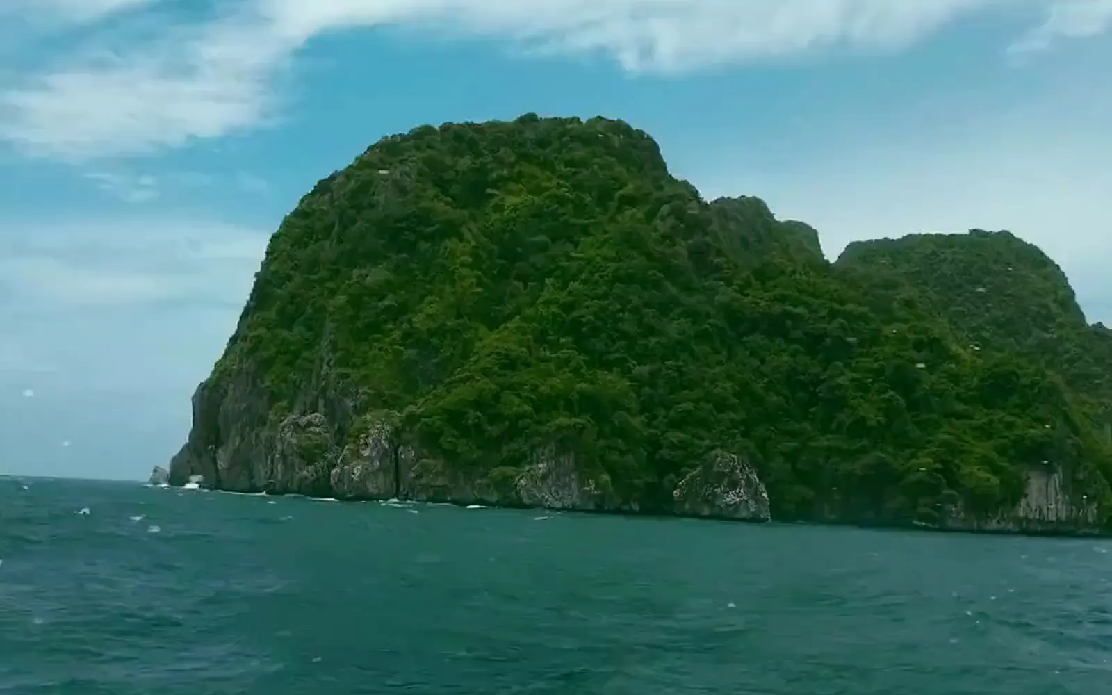 La mer turquoise vue d'un bateau, les falaises au fond